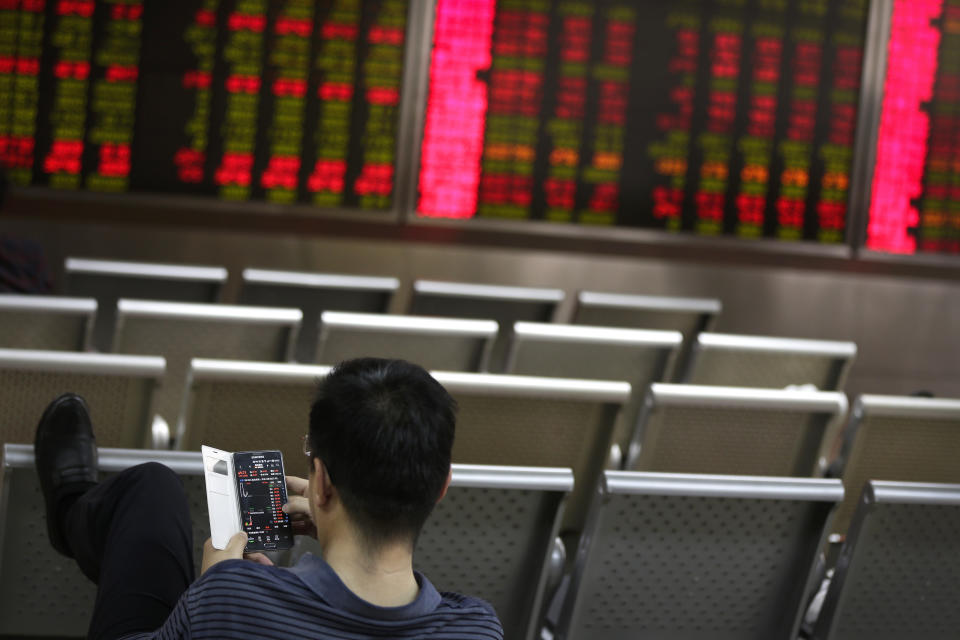 A man checks stock prices through his smartphone at a brokerage house in Beijing, Wednesday, April 24, 2019. Shares were mostly lower in Asia on Wednesday despite the S&P 500’s all-time record high close the day before.(AP Photo/Andy Wong)