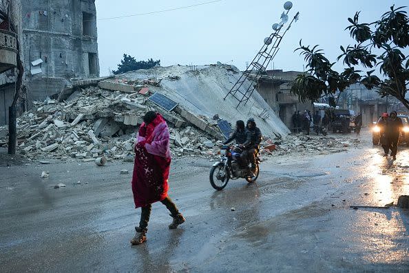 Residents walk along a collapsed building following an earthquake in the town of Jandaris, in the countryside of Syria's northwestern city of Afrin in the rebel-held part of Aleppo province, on February 6, 2023. - Hundreds have been reportedly killed in north Syria after a 7.8-magnitude earthquake that originated in Turkey and was felt across neighbouring countries. (Photo by Rami al SAYED / AFP) (Photo by RAMI AL SAYED/AFP via Getty Images)