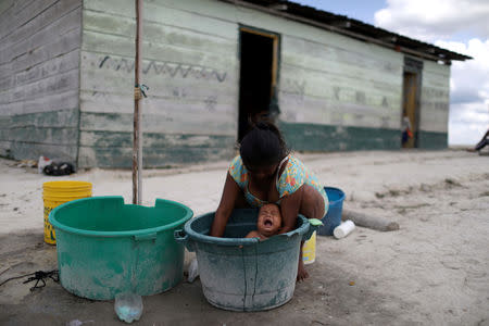 A Venezuelan indigenous woman of Pemon tribe baths her baby in the Brazilian indigenous village Tarau Paru in the border city of Pacaraima, Brazil April 14, 2019. Picture taken April 14, 2019. REUTERS/Pilar Olivares