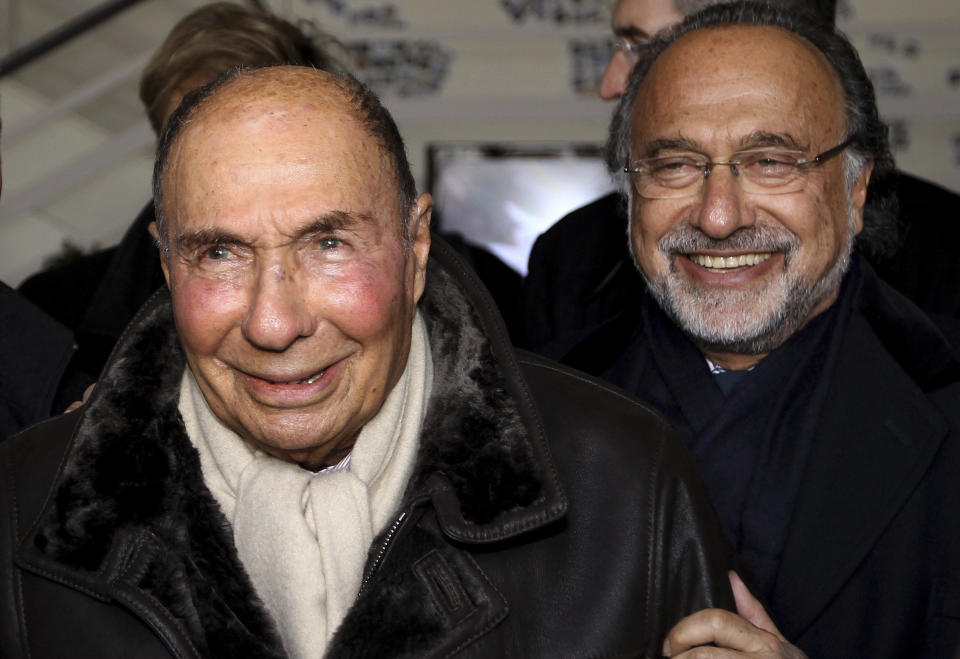 FILE - In this March 4, 2015 file photo, then Dassault Group Chairman and CEO Serge Dassault, left, and his son MP Olivier Dassault react as they visit the factory of French aircraft manufacturer Dassault Aviation in Merignac near Bordeaux, southwestern France. The French billionaire aviation industrialist Olivier Dassault who also served 19 years as a member of parliament died in a helicopter crash along with the pilot, authorities said. Olivier Dassault, 69, was heir to a powerful family business empire that made Falcon private jets and Rafale fighter planes and owned many other businesses including Le Figaro newspaper. (AP Photo/Bob Edme, File)