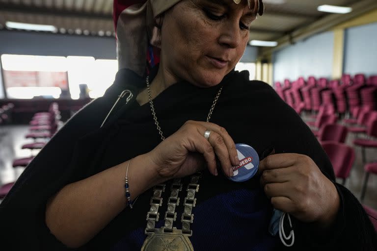 La indígena mapuche María Valdivia Calfuquir se coloca un botón alusivo al "Apruebo" (Archivo)