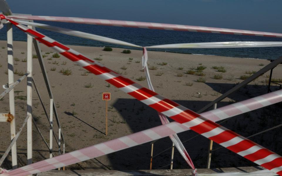 Sign warning people of mines danger is placed at a closed off beach in Odesa  - REUTERS/Valentyn Ogirenko