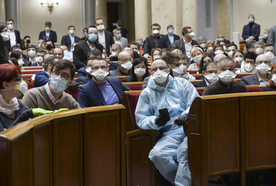 Ukrainian lawmakers wearing face masks to protect against coronavirus attend an extraordinary parliamentary session in Kyiv, Ukraine, Monday, March 30, 2020. Ukraine has been under quarantine since March 12. The new coronavirus causes mild or moderate symptoms for most people, but for some, especially older adults and people with existing health problems, it can cause more severe illness or death. (AP Photo)