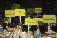 Anti-coup protesters hold placards that read: "Help us finish dictatorship" as they gather outside the U.N. Information Office in Yangon, Myanmar, Sunday, Feb. 14, 2021. Vast numbers of people all over Myanmar have flouted orders against demonstrations to march again in protest against the military takeover that ousted the elected government of Suu Kyi. (AP Photo)