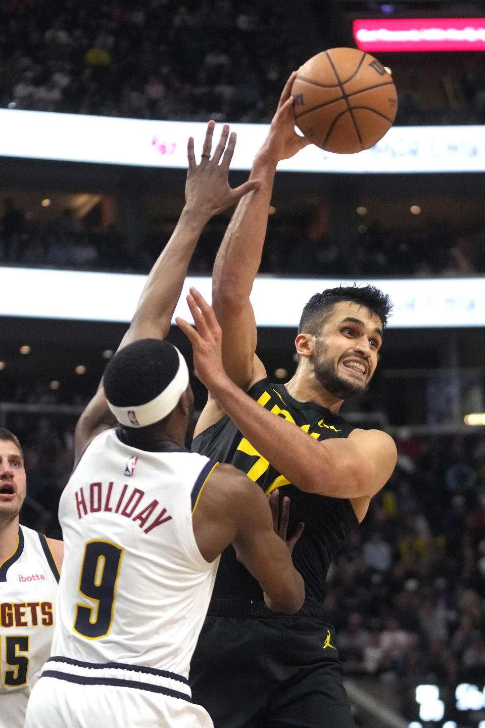 Utah Jazz center Omer Yurtseven, right, passes the ball as Denver Nuggets forward Justin Holiday (9) defends during the second half of an NBA basketball game Tuesday, April 9, 2024, in Salt Lake City. (AP Photo/Rick Bowmer)