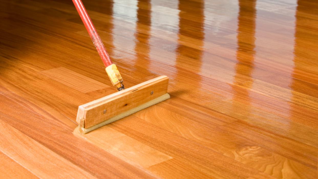 Squeegee Style Brush Applying Clear Polyurethane to Hardwood Floor