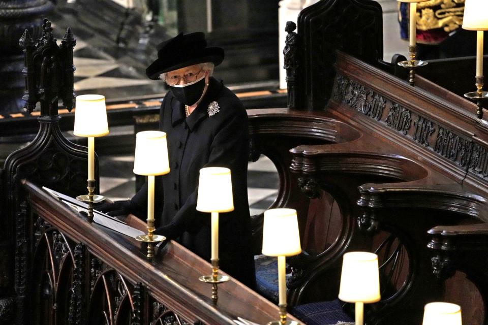 Queen Elizabeth II stands in a pew in St. George's Chapel during the funeral