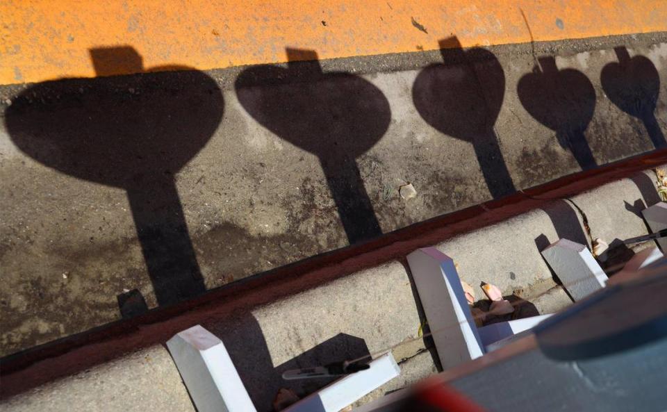 On Wednesday, July 14, 2021, 21 days after the partial collapse of the Champlain Tower South, the recovery efforts continue. The shadows of the memorial wooden hearts bearing the names of the victims of partial collapse of Champlain Towers South are cast on the street’s edge at the memorial site.