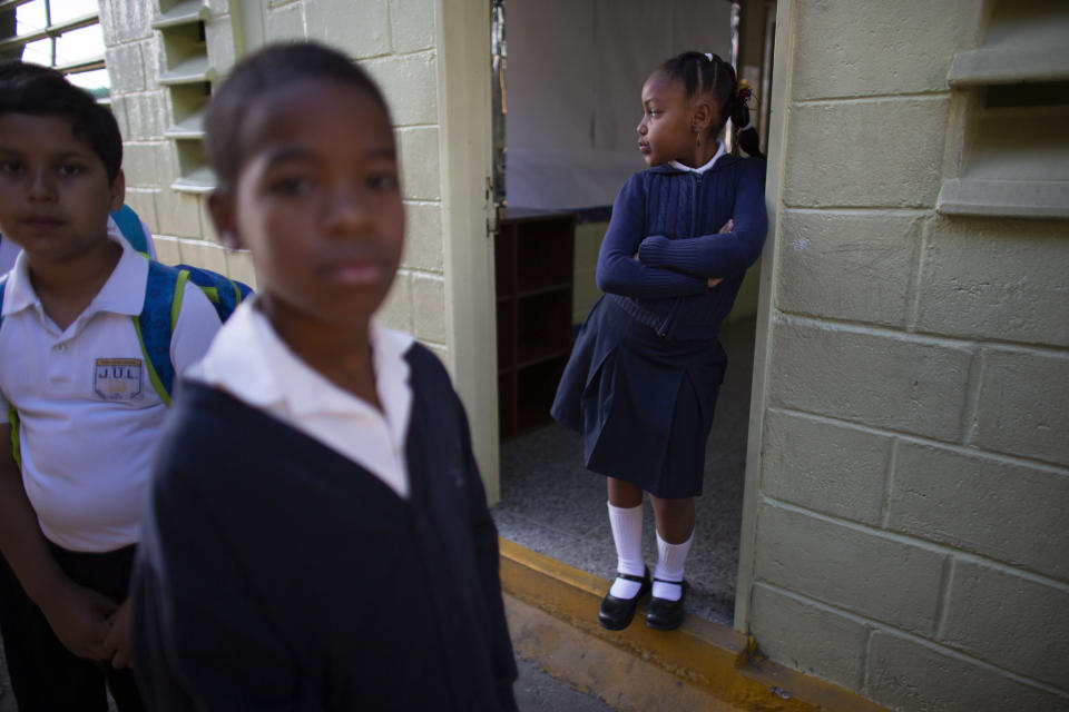 In this Oct. 2, 2019 photo, a girl waits at the entrance of her classroom for her teacher's arrival, on her first day of class at the Jerman Ubaldo Lira public school in Caracas, Venezuela. The school year recently began amid the once-wealthy country's deepening crisis, with more teachers and students abandoning their homeland, leaving classrooms empty. Principal Erika Tortosa said that five years ago, the school tucked inside the narrow streets of the hilltop neighborhood had 1,000 students. (AP Photo/Ariana Cubillos)
