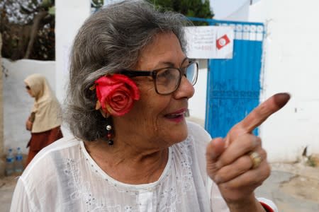 A woman gestures after casting her vote during presidential election in Tunis