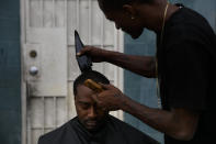 Eric Frierson, 37, gets an haircut from Kenneth Cox, 32, outside an apartment building at the Imperial Courts housing project in the Watts neighborhood of Los Angeles, Wednesday, June 17, 2020. Frierson laments losing focus on becoming a good athlete and falling prey to the "distractions," such as the violence he witnessed or the signs of it. "If you don't see it, you see the aftermath," he said. "You come outside and see the sidewalk stained with blood. It doesn't go anywhere. Every time you go by it, you see it." (AP Photo/Jae C. Hong)