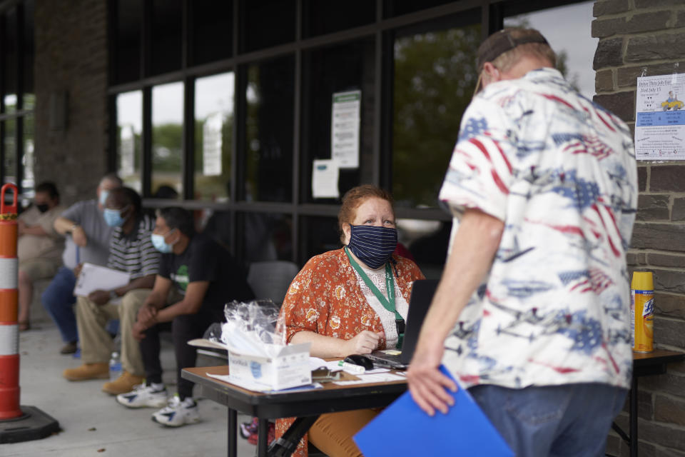 FILE - In this July 15, 2020, file photo, One-stop operator Vickie Gregorio with the Heartland Workforce Solutions talks to a jobseeker outside the workforce office in Omaha, Neb., as others seeking employment wait behind her. On Thursday, Aug. 20, the government reported that the number of workers applying for unemployment climbed back over 1 million last week after two weeks of declines. (AP Photo/Nati Harnik, File)