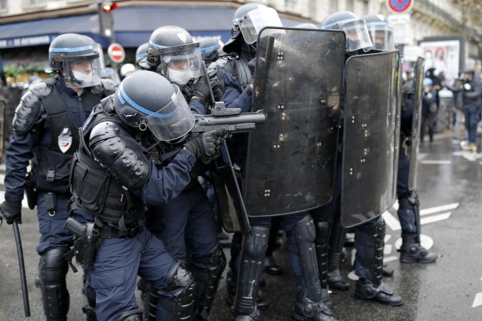 A riot police officer aims during a protest against a proposed bill , Saturday, Dec.12, 2020 in Paris. The bill's most contested measure could make it more difficult for people to film police officers. It aims to outlaw the publication of images with intent to cause harm to police. The provision has caused such an uproar that the government has decided to rewrite it. Critics fear the law could erode press freedom and make it more difficult to expose police brutality. (AP Photo/Lewis Joly)