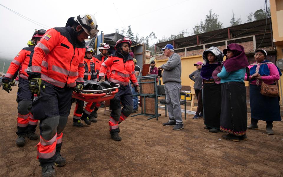 Rescue workers recover the remains of a child in Alausi - Dolores Ochoa/AP