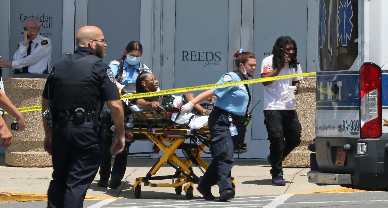 Gastonia Police officers at the scene of a shooting at Eastridge Mall on Friday, June 10, 2022. Paramedics remove one of the injured in the background.