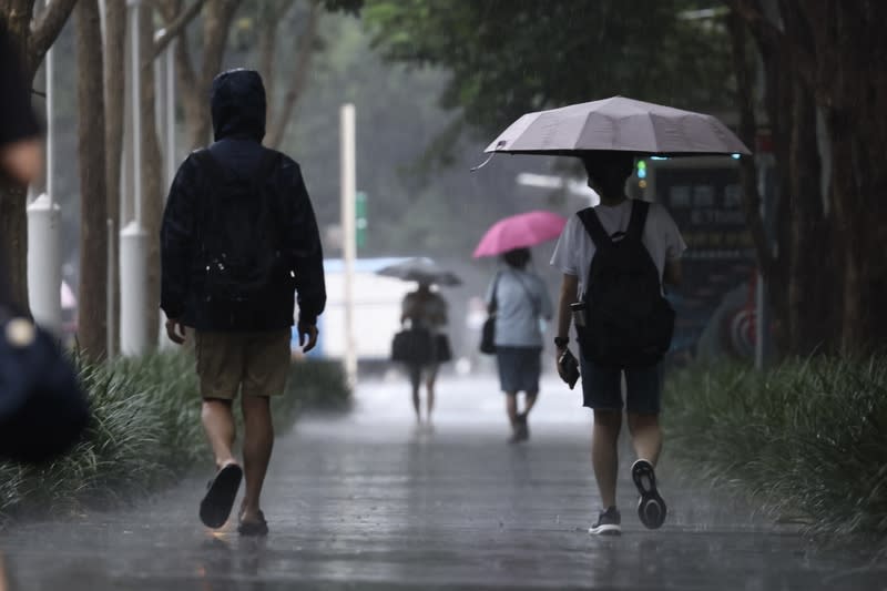 台北市區午後降雨（1） 中央氣象署9日下午針對大台北等地區發布大雨特 報，午後對流雲系發展旺盛，台北市松山區下午降下 雨勢，街頭民眾撐傘、穿外套擋雨。 中央社記者翁睿坤攝  113年7月9日 