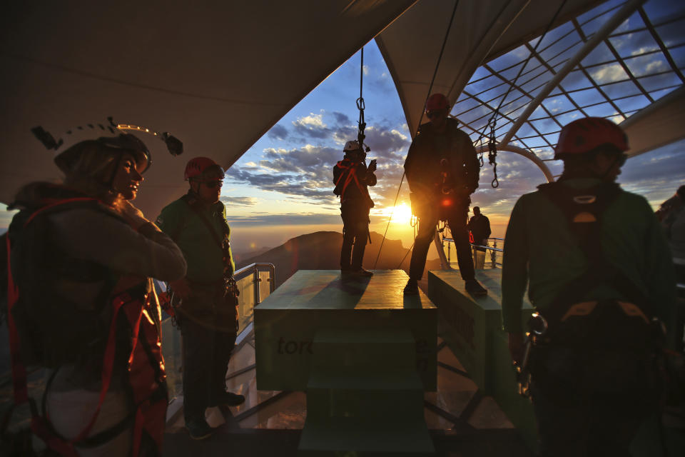 In this Wednesday, Jan. 31, 2018 photo, thrill-seekers prepare to try out a new zip line, on the peak of Jebel Jais mountain, 25 kms (15.5 miles) north east of Ras al-Khaimah, United Arab Emirates. The UAE is claiming a new world record with the opening of the world's longest zip line, measuring 2.83 kilometers (1.76 miles) in length. Guinness World Records officials certified the zip line on Thursday, the same day the attraction opened to the public. (AP Photo/Kamran Jebreili)