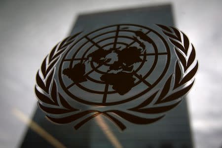 The United Nations headquarters building is pictured though a window with the UN logo in the foreground in the Manhattan borough of New York August 15, 2014. REUTERS/Carlo Allegri