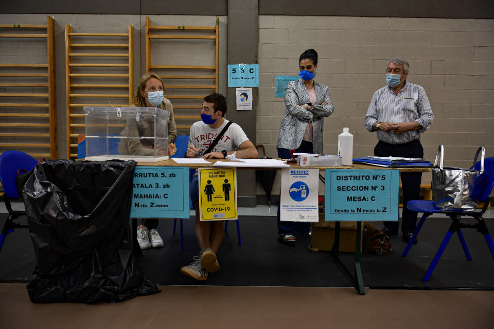 Polling station staff wear face masks to help curb the spread of the coronavirus while waiting for people to vote in the Basque regional election in the village of Durango, northern Spain, Sunday, July 12, 2020. Basque authorities display special rules for protection against the coronavirus. (AP Photo/Alvaro Barrientos)