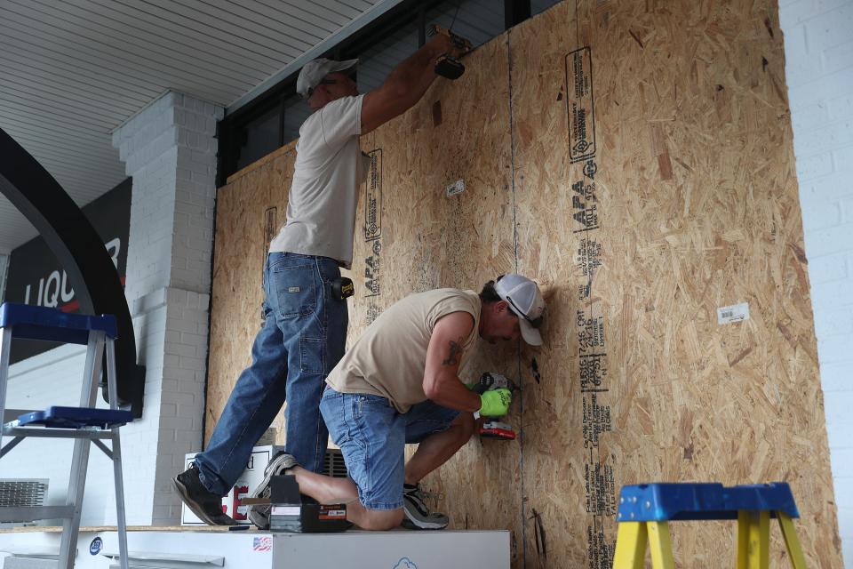 Wesley Jacobs and David Bouillion board up the windows on a business before the possible arrival of Hurricane Laura on August 25, 2020, in Lake Charles, La.