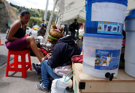 A Venezuelan migrant cleans her daughter's feet at the Rumichaca International Bridge in Ecuador August 17, 2018. REUTERS/Luisa Gonzalez