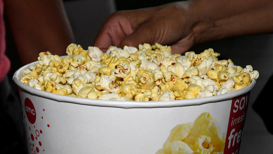 LAS VEGAS, NEVADA - AUGUST 20:  A customer gets a bucket of popcorn before seeing a movie at AMC Town Square 18 on August 20, 2020 in Las Vegas, Nevada. AMC Theatres reopened more than 100 of its movie theaters across the United States today, with new safety precautions in place, for the first time since closing in March because of the coronavirus (COVID-19) pandemic. In celebration of its 100th anniversary, the world's largest theater chain is welcoming guests back with a "Movies in 2020 at 1920 Prices" promotion for one day by offering 15-cent tickets to classic and previously-released films and USD 5 concession items. Starting on August 21, older movies will be shown for USD 5 a ticket. According to AMC, enhanced cleaning and safety protocols include disinfecting theaters before each show, mandatory face coverings for employees and customers, upgraded air filtration systems where possible, and high-touch points cleaned throughout the day. Hand sanitizer and disinfectant wipes are available throughout the theaters, auditoriums are at 40 percent capacity or less, and concession menus have been simplified for shorter lines and quicker service.  (Photo by Ethan Miller/Getty Images)