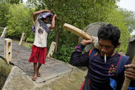 Aslori, left, carries a toilet he just removed from a relative's house near the home his family abandoned in Mondoliko, Central Java, Indonesia, Monday, Sept. 5, 2022. He and his family moved to drier land, becoming climate migrants as many of their neighbors had before them. (AP Photo/Dita Alangkara)