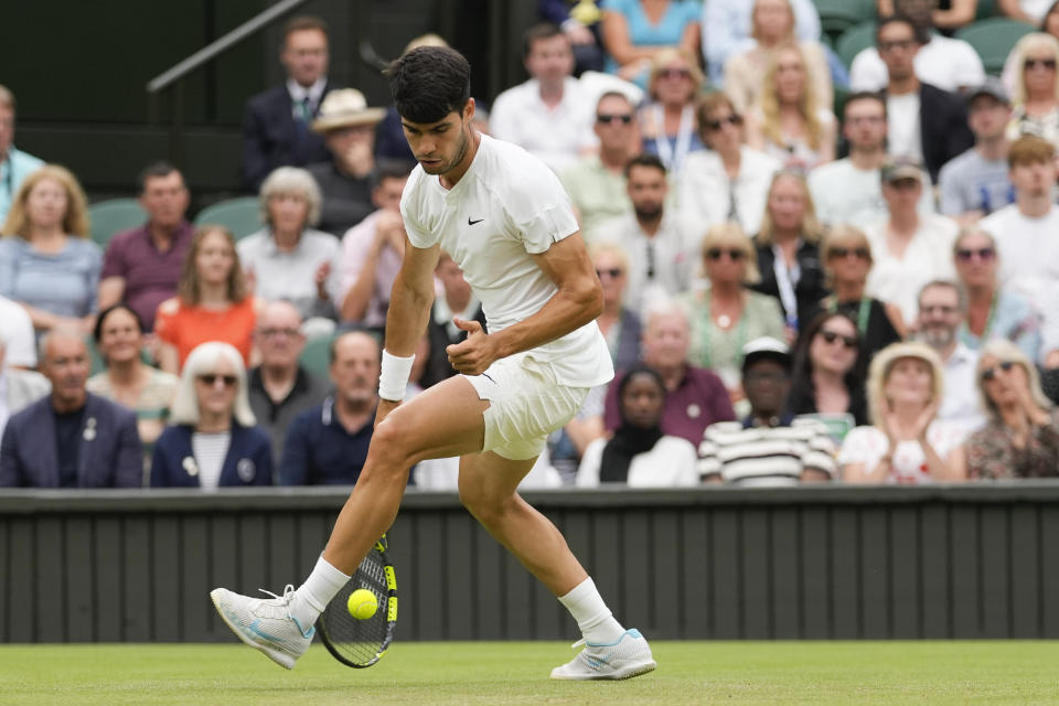 Spain's Carlos Alcaraz plays shot between his legs to Francis Tiafoe of the United States during their third round match at the Wimbledon tennis championships in London, Friday, July 5, 2024. (AP Photo/Alberto Pezzali)