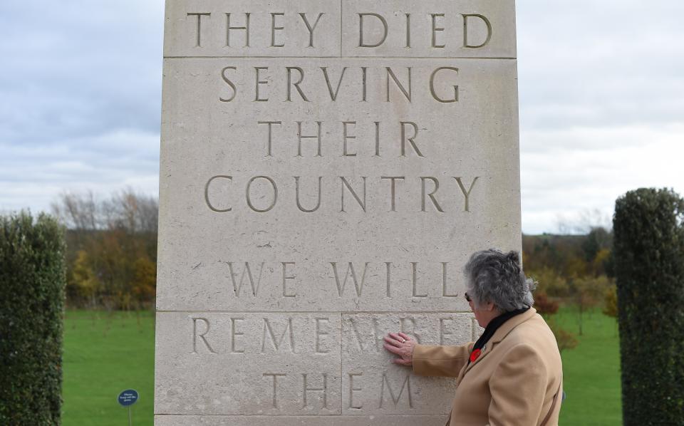 A woman touches a memorial plaque after the Armistice Day service of remembrance with members of the armed forces and veterans at the National Memorial Arboretum in Alrewas, central England on November 11, 2015. The Armed Forces Memorial is to undergo a year-long programme of repairs and improvements, starting on November 12, 2015.&nbsp;