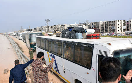 People welcome evacuees from the two Shi'ite villages of al-Foua and Kefraya, upon their arrival by buses to government-controlled Aleppo, in this handout picture provided by SANA on April 12, 2017. SANA/Handout via REUTERS