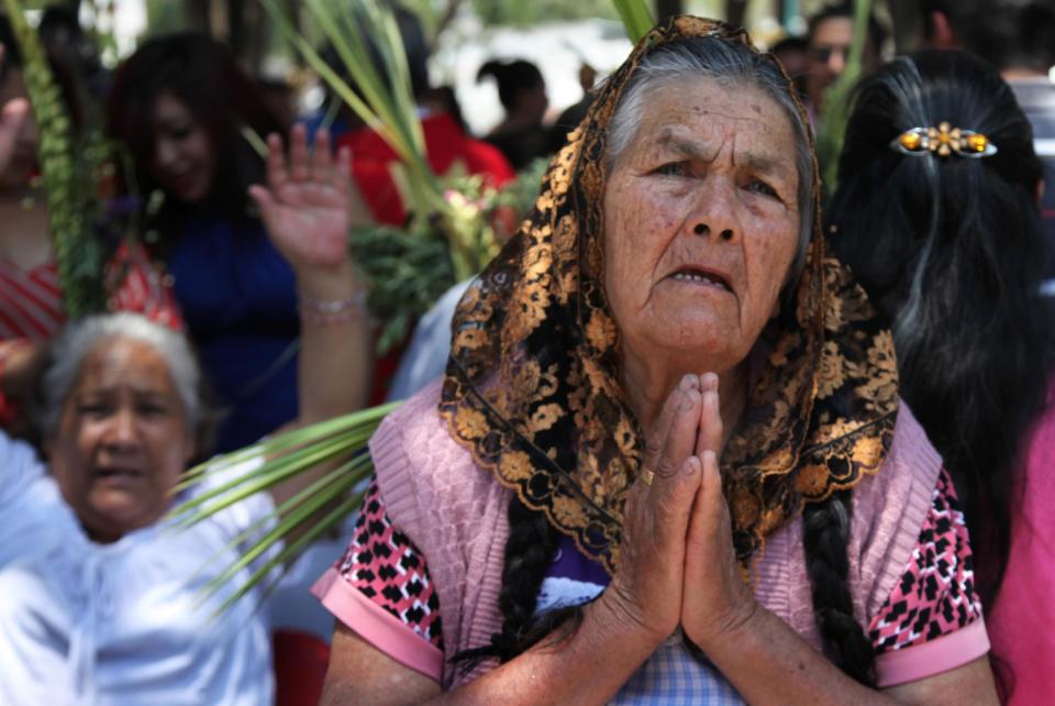 A woman prays during a Palm Sunday procession in the San Mateo neighborhood of Mexico City, Sunday, April 13, 2014. For Christians, Palm Sunday marks Jesus Christ's entrance into Jerusalem, when his followers laid palm branches in his path, prior to his crucifixion. (AP Photo/Marco Ugarte)