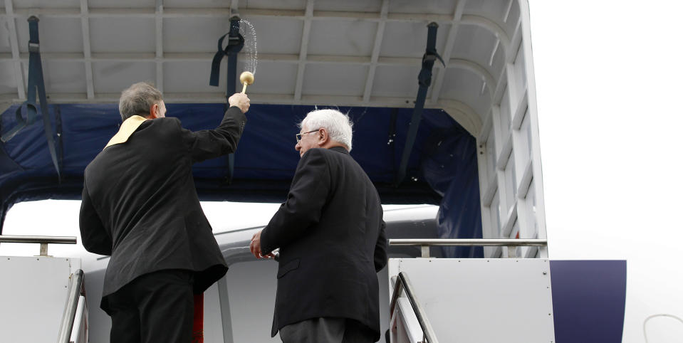 Fr. Stanislaw Michalek, left, using holy water as he blesses a LOT Polish Airlines Boeing 787 with Marian Strutynski during a delivery ceremony Wednesday, Nov. 14, 2012, at Paine Field in Everett, Wash. LOT Polish Airlines took delivery of its first Boeing 787 and plans to fly early next year on routes between Poland and New York, Chicago and Toronto. Poland's LOT was Europe's first airline to purchase the new plane with an order for eight. Boeing says the 787 is the first mid-size plane capable of flying long-range routes, allowing airlines to open new, non-stop flights. (AP Photo/Elaine Thompson)