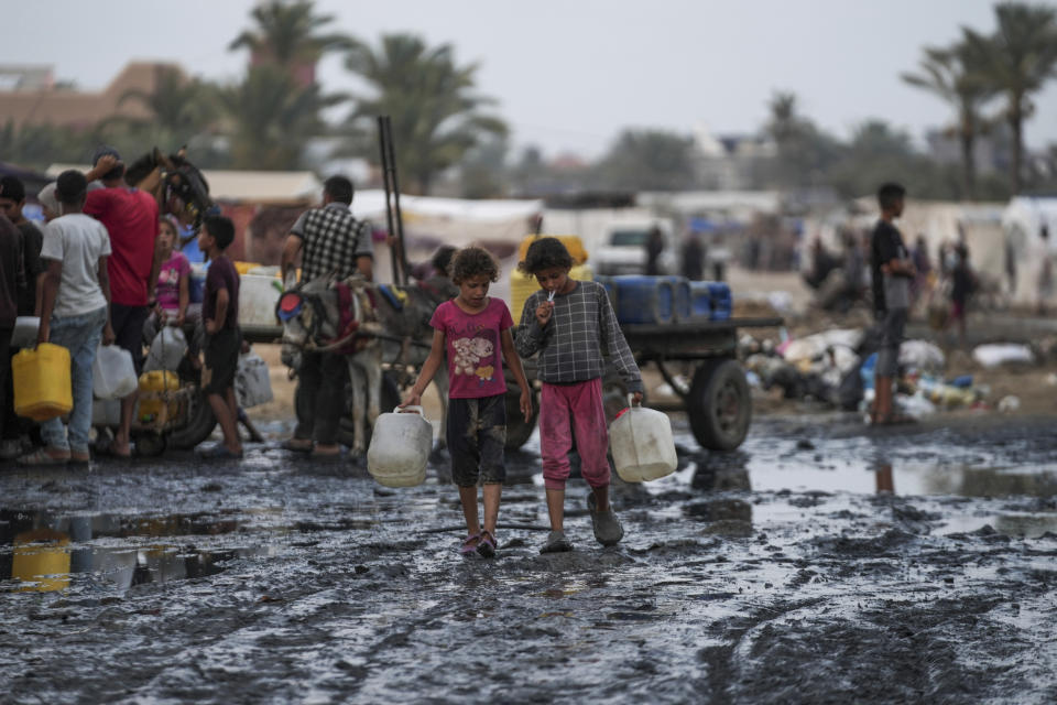 Palestinians gather to fill water jugs near one of the strip's few functioning desalination plants in Deir al-Balah, Gaza Strip, Thursday, June 20, 2024. Israel's war in Gaza has decimated the strip's sanitation system while simultaneously displacing the vast majority of the population, leaving many Palestinians living in tent camps nearby streams of sewage and growing piles of garbage. (AP Photo/Abdel Kareem Hana)