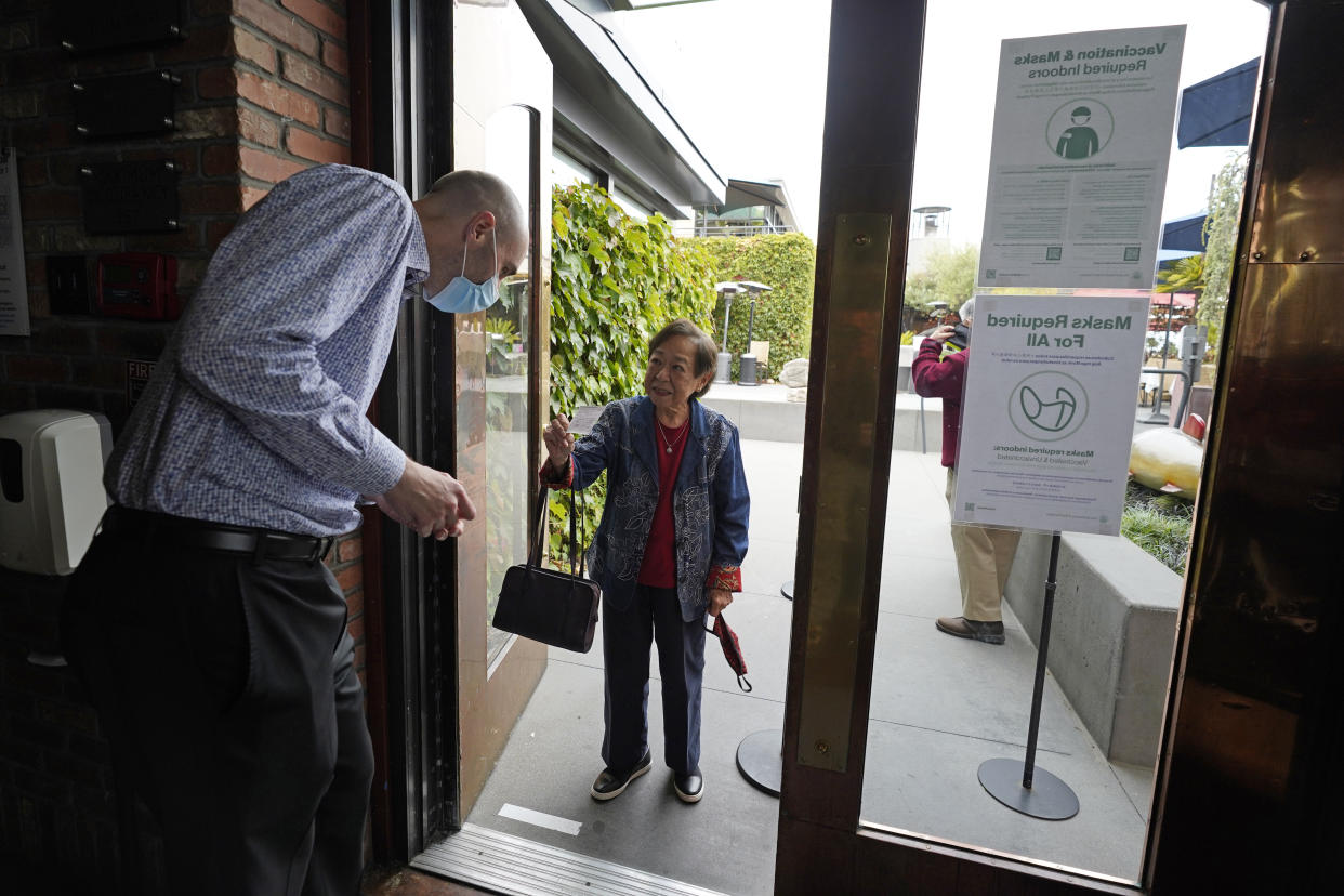 Host Jason Pryor checks the vaccination record of Audrey Tong as she enters the Waterbar restaurant on Aug. 20, 2021, in San Francisco. California is seeing lower coronavirus transmission than other U.S. states as virus cases and hospitalizations decline following a summer surge. State health experts say relatively high vaccination rates ahead of the arrival of the delta variant made a difference. (AP Photo/Eric Risberg)