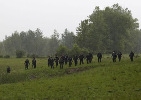 Law enforcement officers search a field near Willsboro, New York June 9, 2015. REUTERS/Chris Wattie