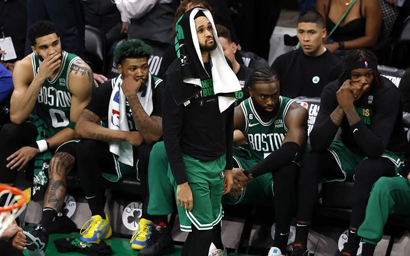Boston Celtics guard Derrick White, center, stands in front of the bench as his teammates sit behind him