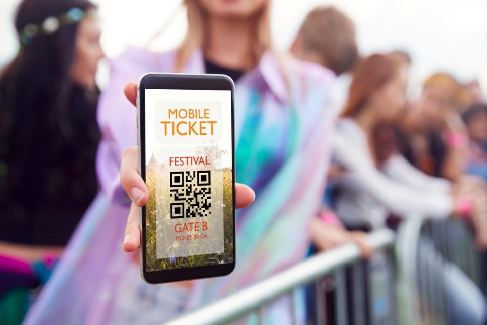 Woman holding phone showing a mobile ticket to a festival