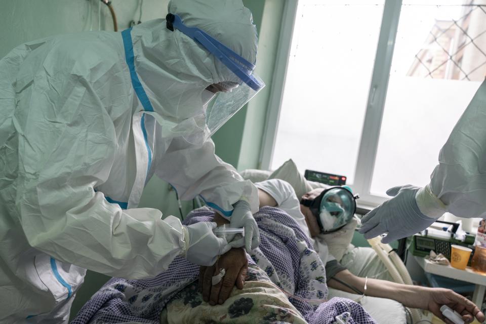 In this photo taken on Monday, May 4, 2020, a nurse, wearing a special suit to protect against coronavirus, administers drugs to a patient with coronavirus at an intensive care unit at a regional hospital in Chernivtsi, Ukraine. Ukraine's troubled health care system has been overwhelmed by COVID-19, even though it has reported a relatively low number of cases. (AP Photo/Evgeniy Maloletka)