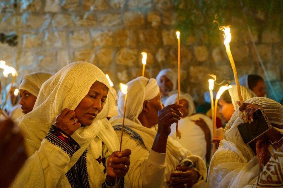 An Ethiopian woman holds a candle while praying during the Holy Fire Ceremony of the Ethiopian Orthodox Church in Jerusalem