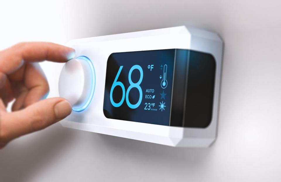 Closeup of hand setting a thermostat's temperature