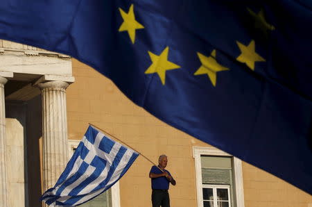 A protester waves a Greek flag at the entrance of the parliament building during a rally calling on the government to clinch a deal with its international creditors and secure Greece's future in the Eurozone, in Athens, Greece, in this June 22, 2015 file photo. REUTERS/Yannis Behrakis/Files