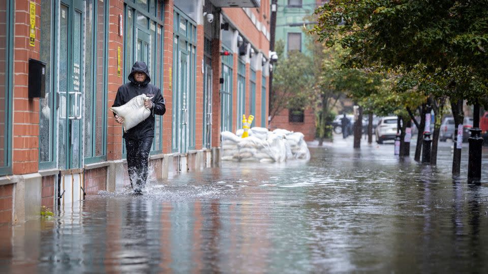 A person carries sandbags on a flooded sidewalk in Hoboken, New Jersey, on Friday. - Stefan Jeremiah/AP