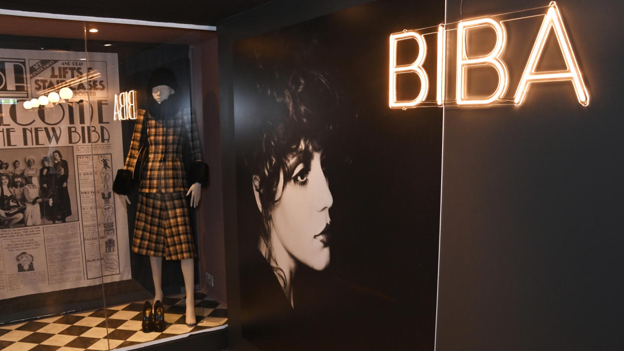  The Biba Story: 1964-1975 exhibition at the Fashion & Textile Museum, showing clothes in a display case, a neon sign saying 'Biba' and a black-and-white photo of a woman's head. 