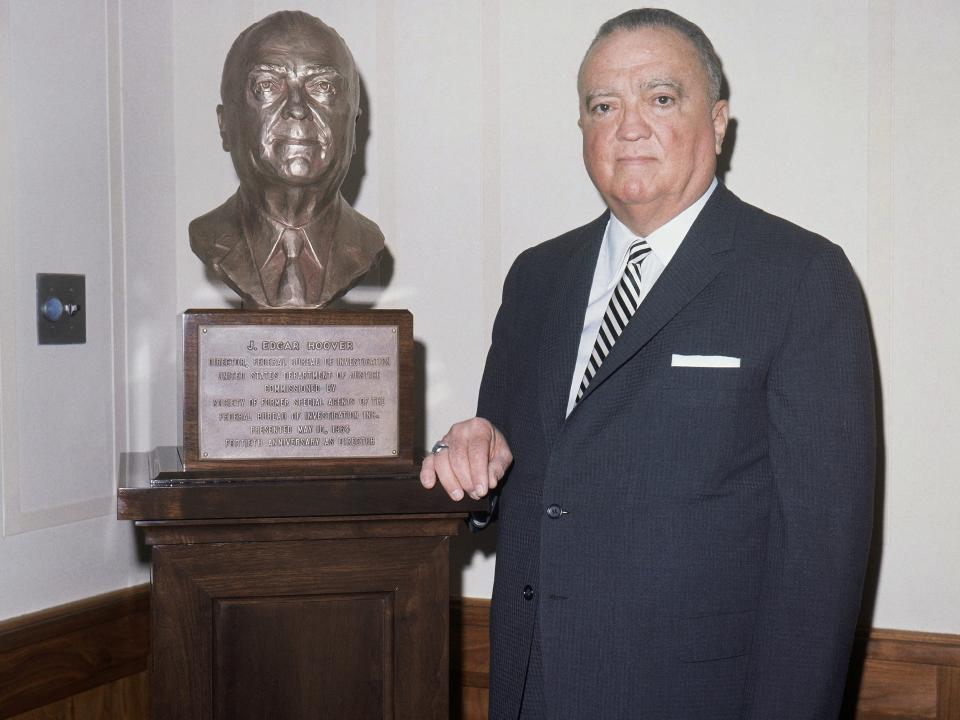 J. Edgar Hoover standing beside a sculpture of himself.