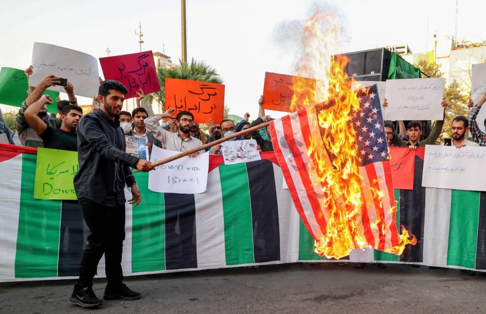 An Iranian student from the Islamic Basiji volunteer militia burns a US flag in Iran’s capital Tehran during a protest against the US president’s visits to Israel and Saudi Arabia (AFP via Getty)