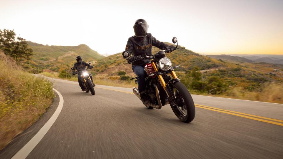 a couple of people ride motorcycles down a mountainous road