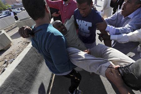 People carry a man who was injured when Libyan militiamen opened fire into a crowd of protesters in Tripoli November 15, 2013. REUTERS/Stringer