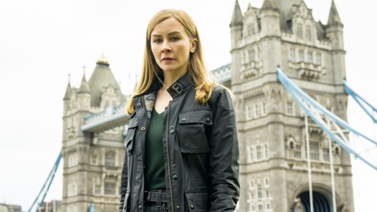  Eva-Jane Willis as Smitty in front of a bridge in London for FBI: International Season 3x11 cropped. 