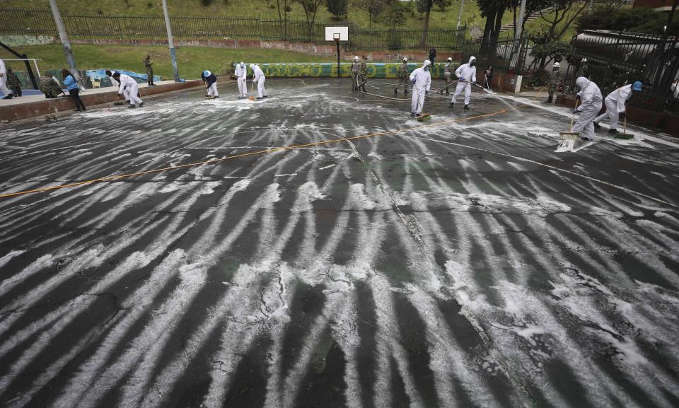 Soldiers and residents disinfect a basketball court at a park amid the spread of the new coronavirus in the San Cristobal area of Bogota, Colombia, Tuesday, June 16, 2020. (AP Photo/Fernando Vergara)