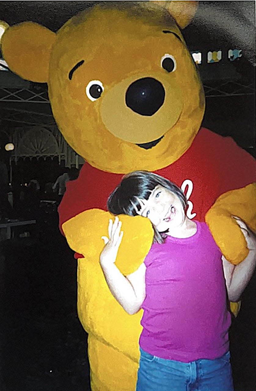 megan posing with winnie the pooh at disney world as a kid 30 years ago